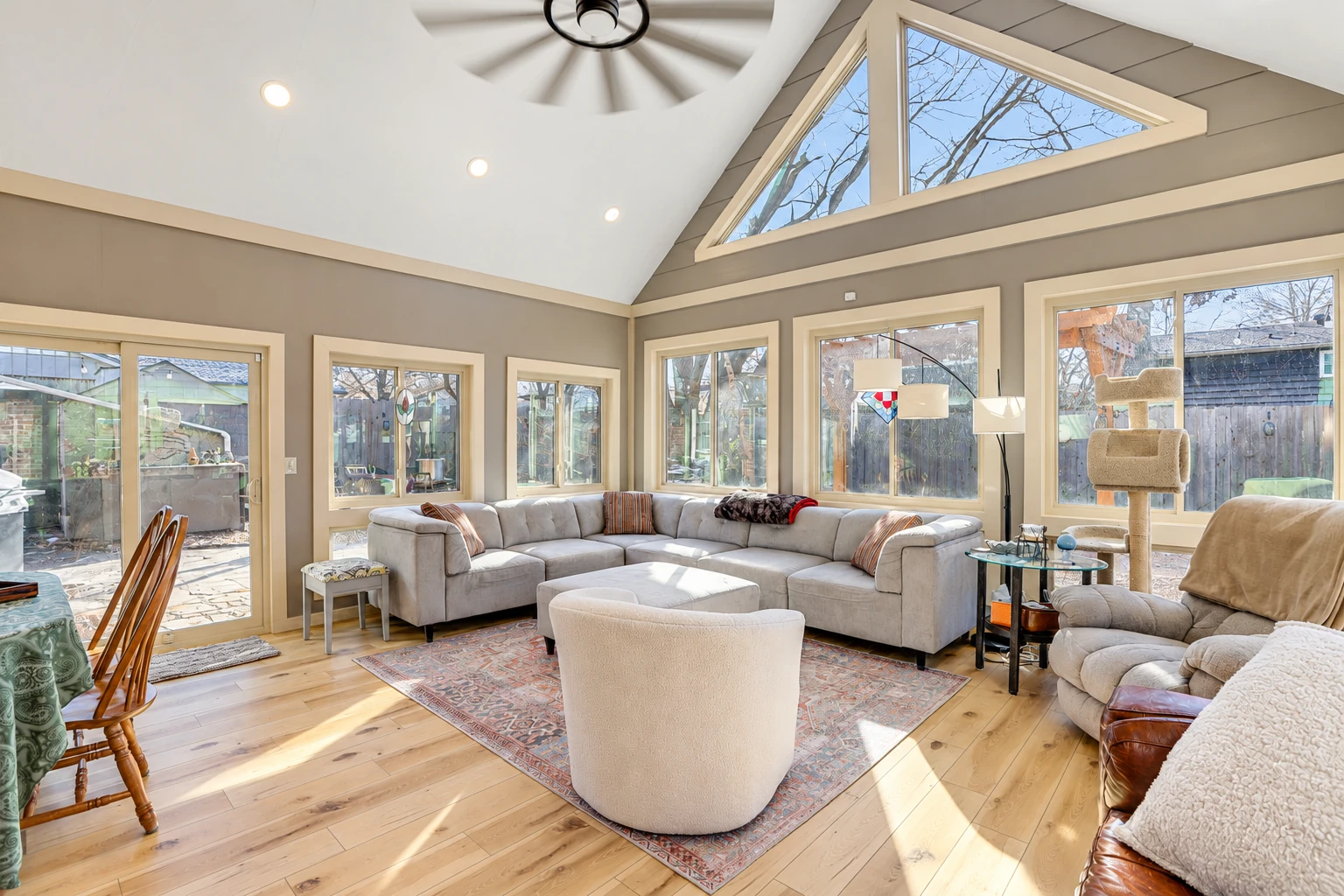 Four-season sunroom with a vaulted ceiling, triangular clerestory windows, and a sectional sofa.