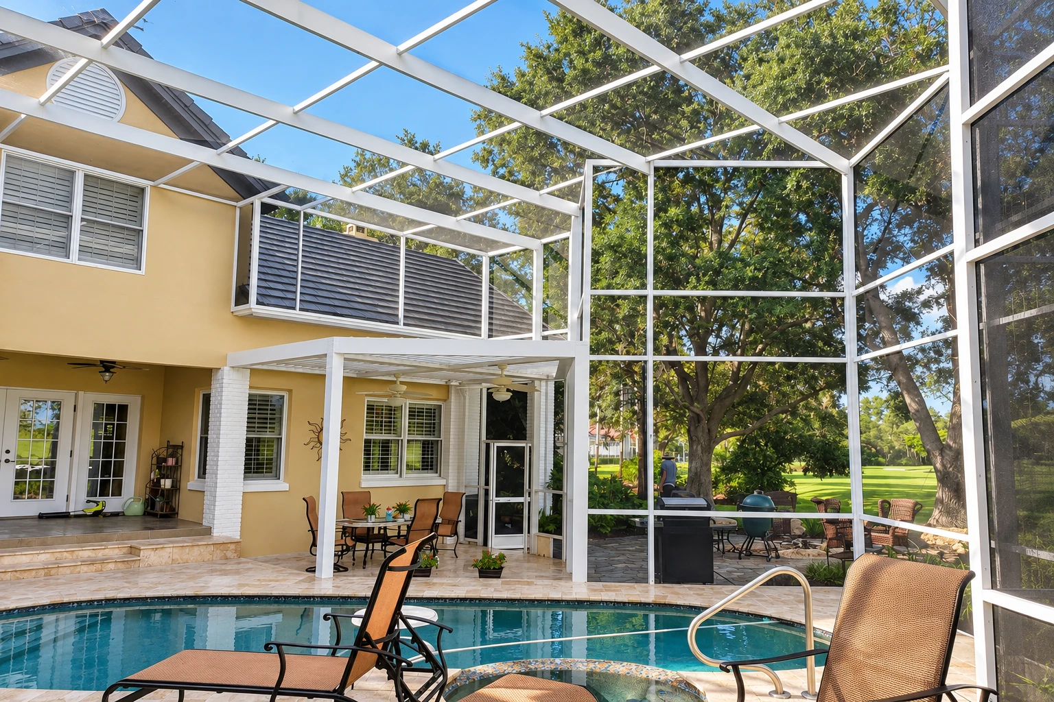 Screen room with white mesh walls and roof enclosing a poolside patio with loungers and outdoor dining.